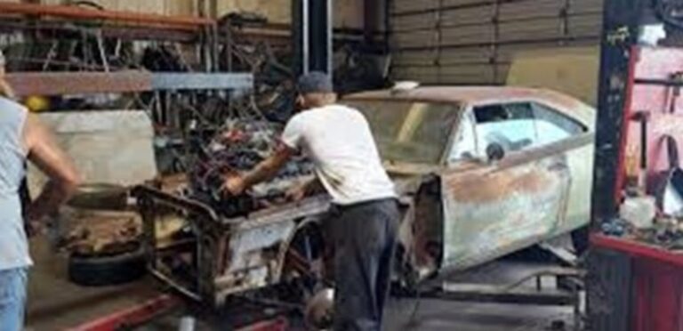 2 men putting an engine into a classic car