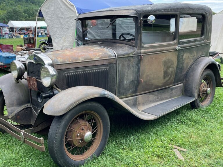 Unrestored vintage Ford sedan car on grass