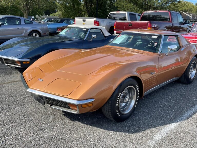 2 1970 Corvettes in a parking lot, 1 orange and 1 blue