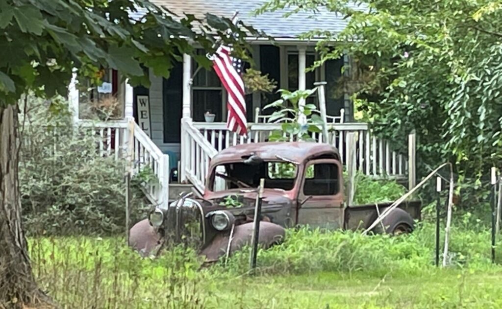 Rusting old Ford truck in front yard
