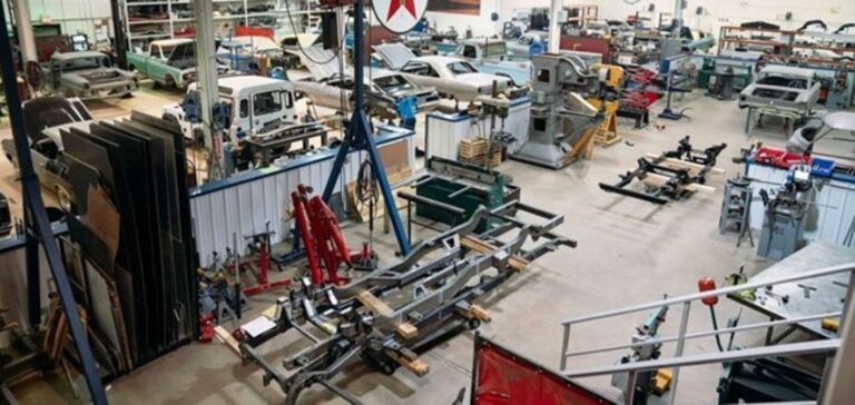 Inside a classic car restoration shop with cars, and parts