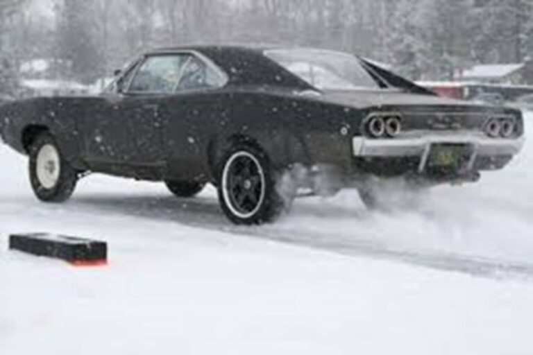 Black '60s Dodge Charger driving on a snow road in the snow