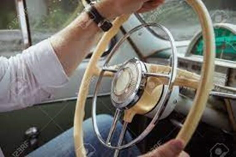 A man holding onto a classic car steering wheel