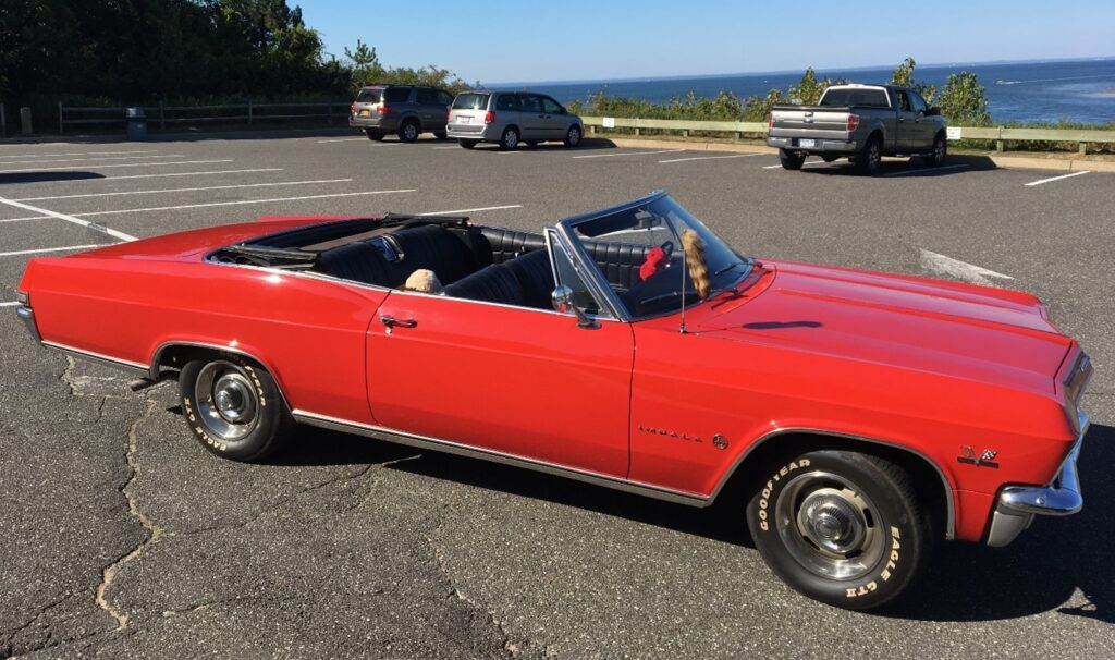 Red 1965 Chevrolet Impala convertible in a parking lot