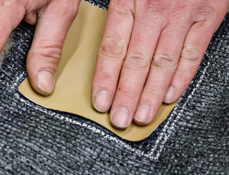 Placing beige vinyl on the back of the carpet repair area