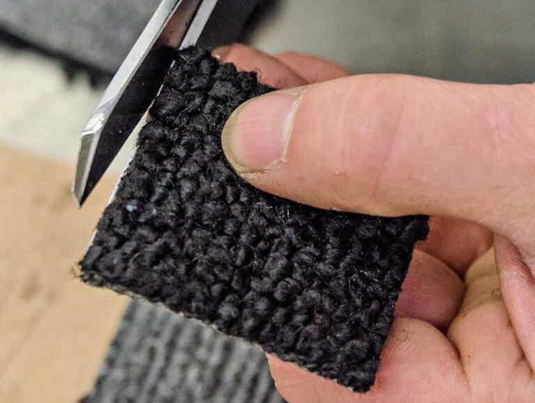 Trimming edge of carpet strands on patch for carpet repair