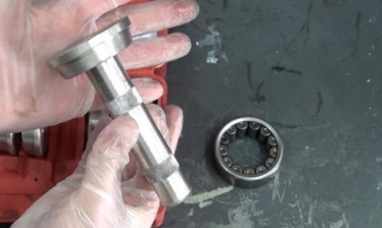 A person holding a bearing installing tool over a axle bearing