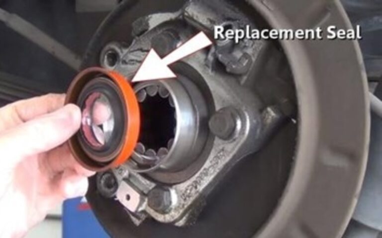 A person holding the new rear differential axle seal over the rear axle bearings
