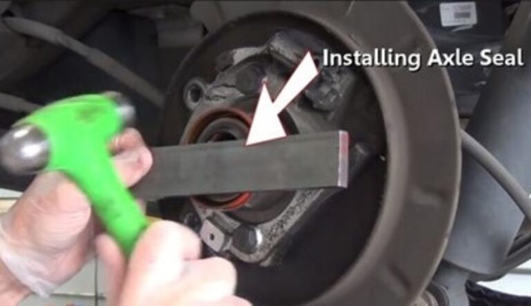A person holding a hammer and metal bar of teh bearing seal to install