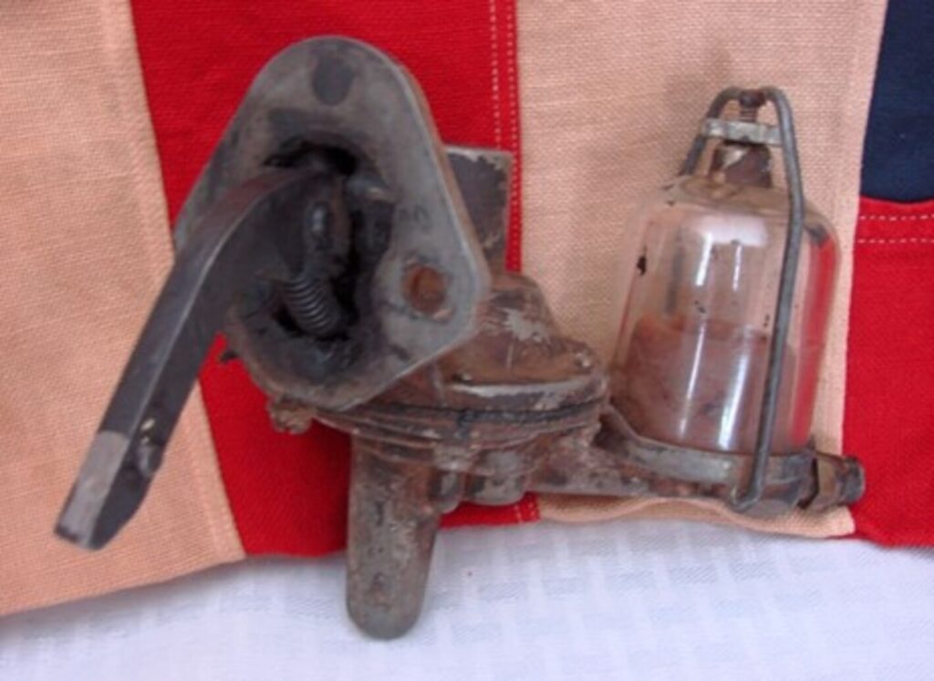 An antique engine fuel pump and filter laying on top of American flag