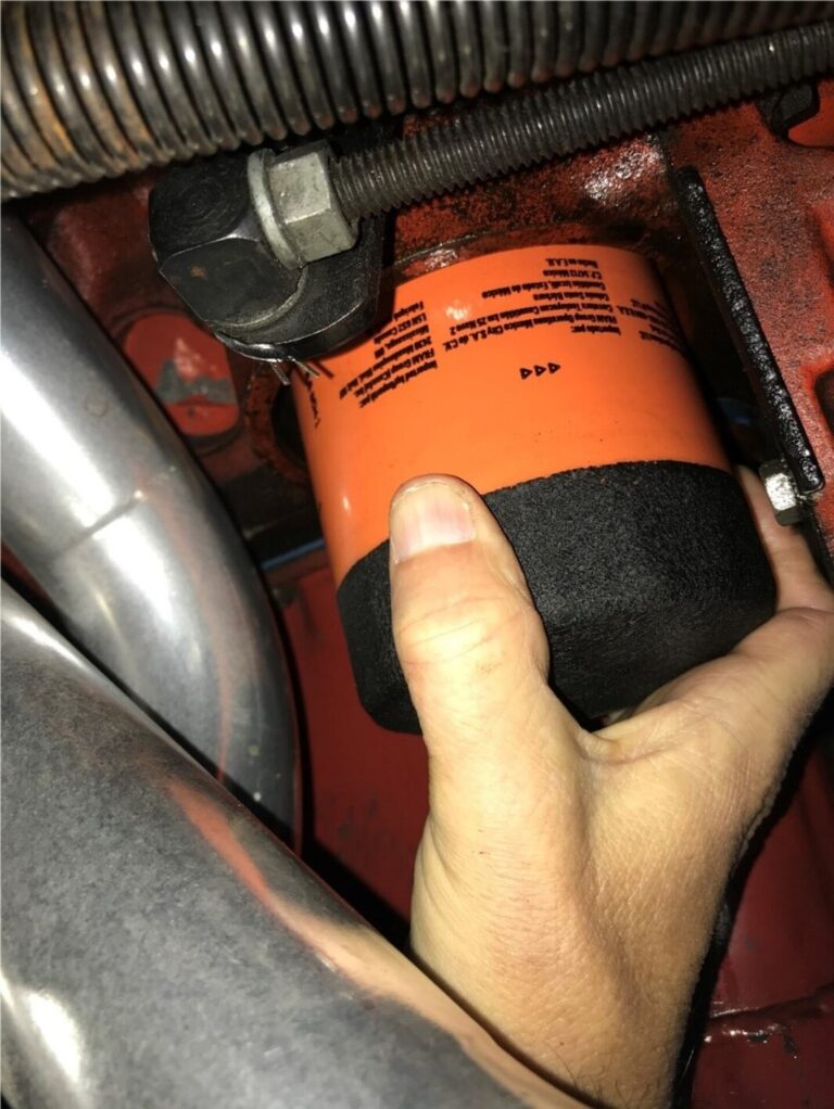 Installing an orange oil filter onto a Chevrolet engine