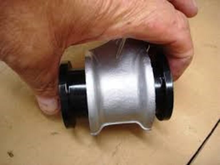A erson holding a black suspension bushings on a control arm