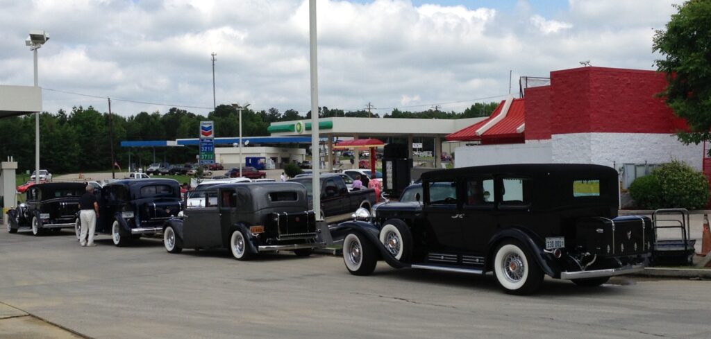 Classic black Cadillacs at a gas station on a road trip