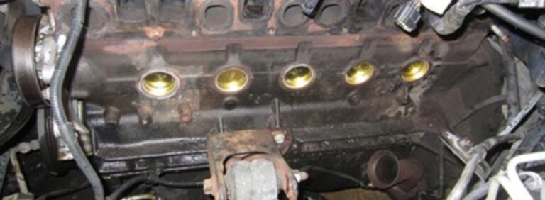 The side of a car engine showing the brass freeze out plugs