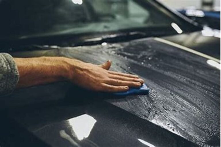 A person using a clay bar on the hood of a car