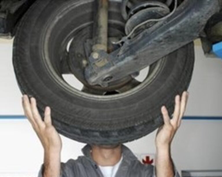 Man holding rear tire mounted to axle to test tire play