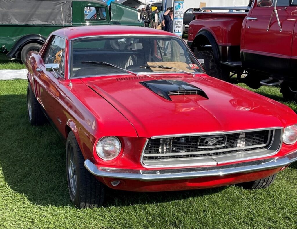 Red 67 Ford Mustang for sale in a field