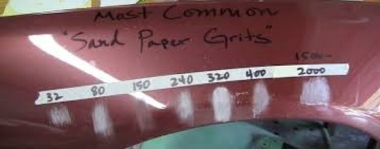 A burgundy car fender showing the scratches made by different grit sandpaper