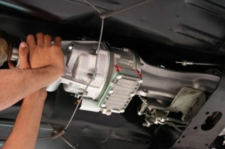 A mecahnic installing an overdrive unit onto the rear of a car transmission