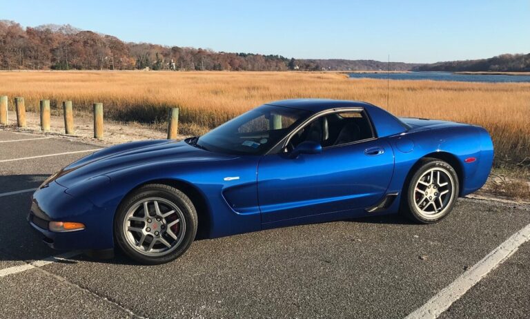 Blue Chevy Corvette C5 parked in a lot next to some mashland