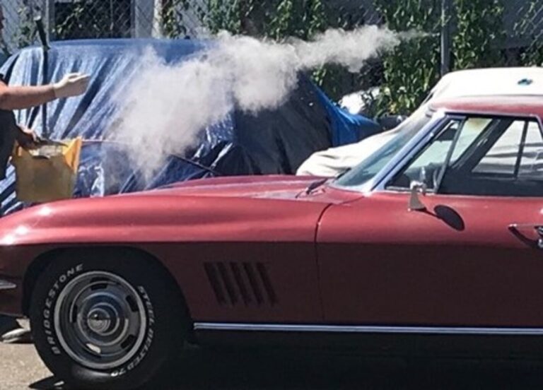 Person throwing dust on a Corvette to fake a barn find restoration shop scams