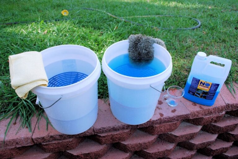 2 buckets, one wit hwaterr and the other with car wash on a wall with a container of car wash