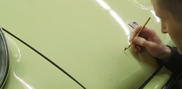 Touching up paint on the hood on a yellow Porsche to maintain a classic car's value