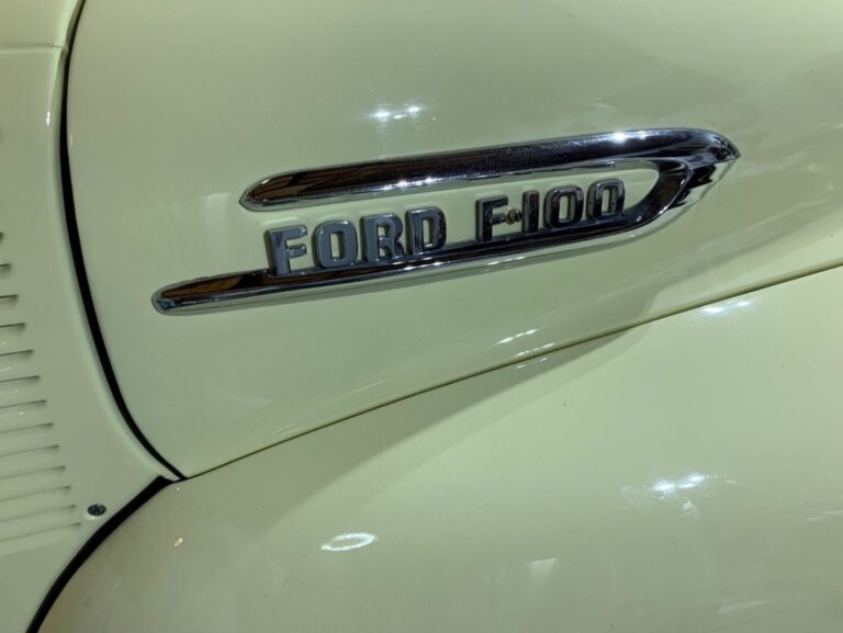 The chrome side hood emblem with Ford F-100 on yellow pickup truck