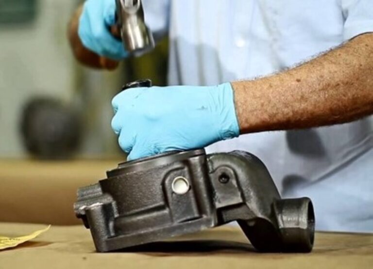 Mechanic using a hammer on socket to remove the water pump fan hub