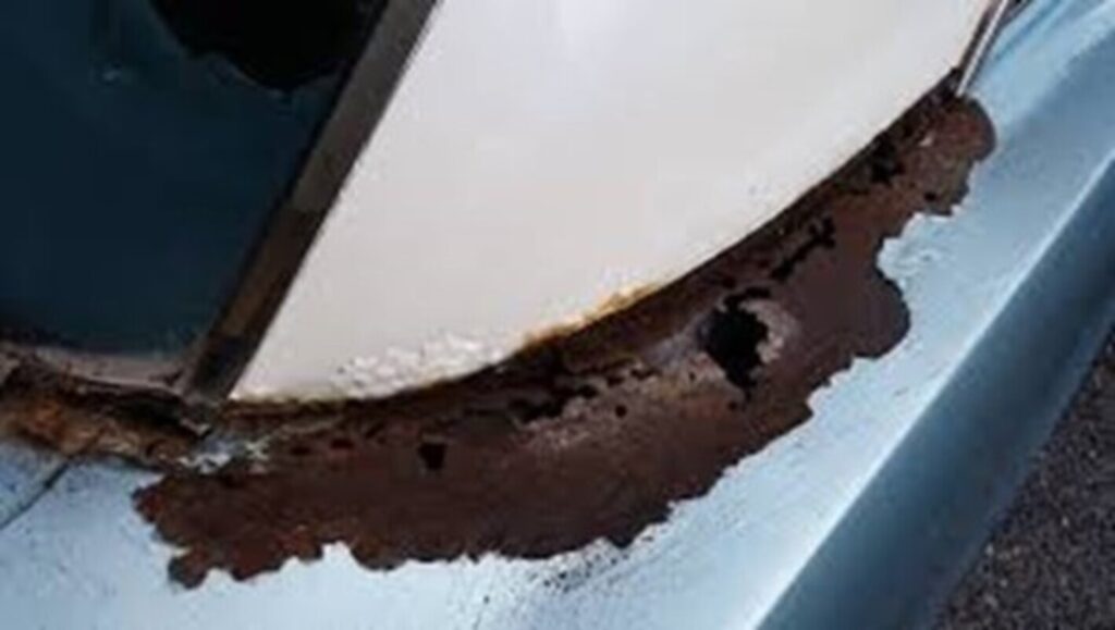 Rust on quarter panel of a blue car with white vinyl top
