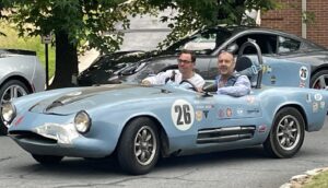 Old English race car driving thru a car show