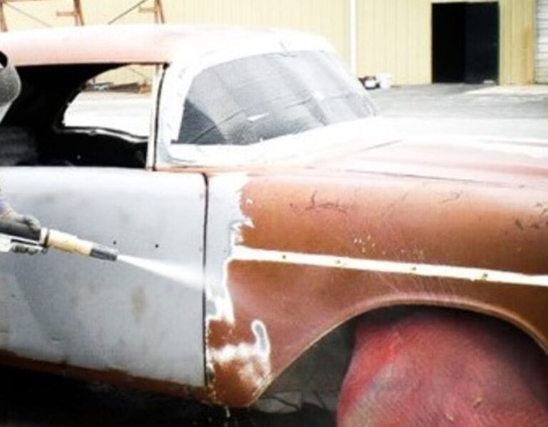 Surface rust being remove from side panels of a car with sand blasting