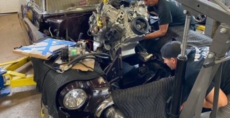 Mechannics working to reisntall a car engine int oa black car after engine rebuilding