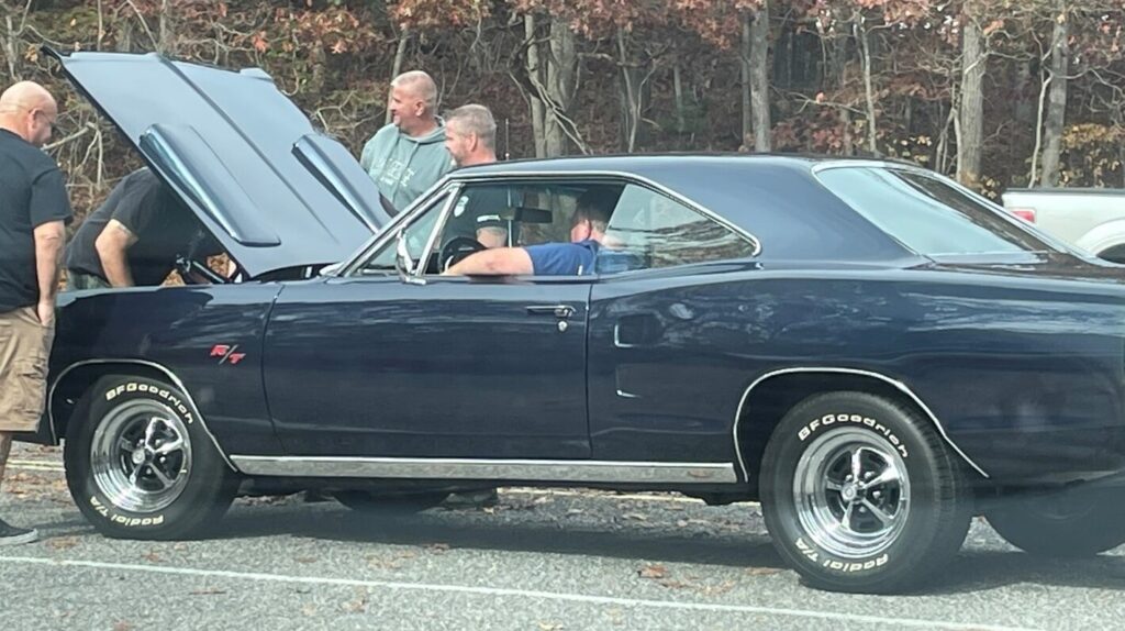 Blue Plymouth R/T on the side of the road with men looking under the as the car will not start