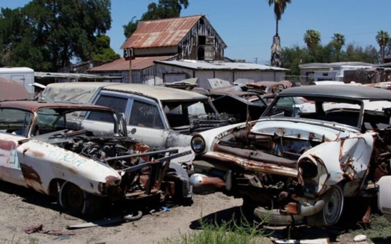 Old cars sitting in pieces at a junkyard