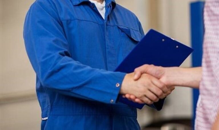 A repair shop owner in blue overalls and holding a clipboard shaking hands with a customer-understanding scammer methods