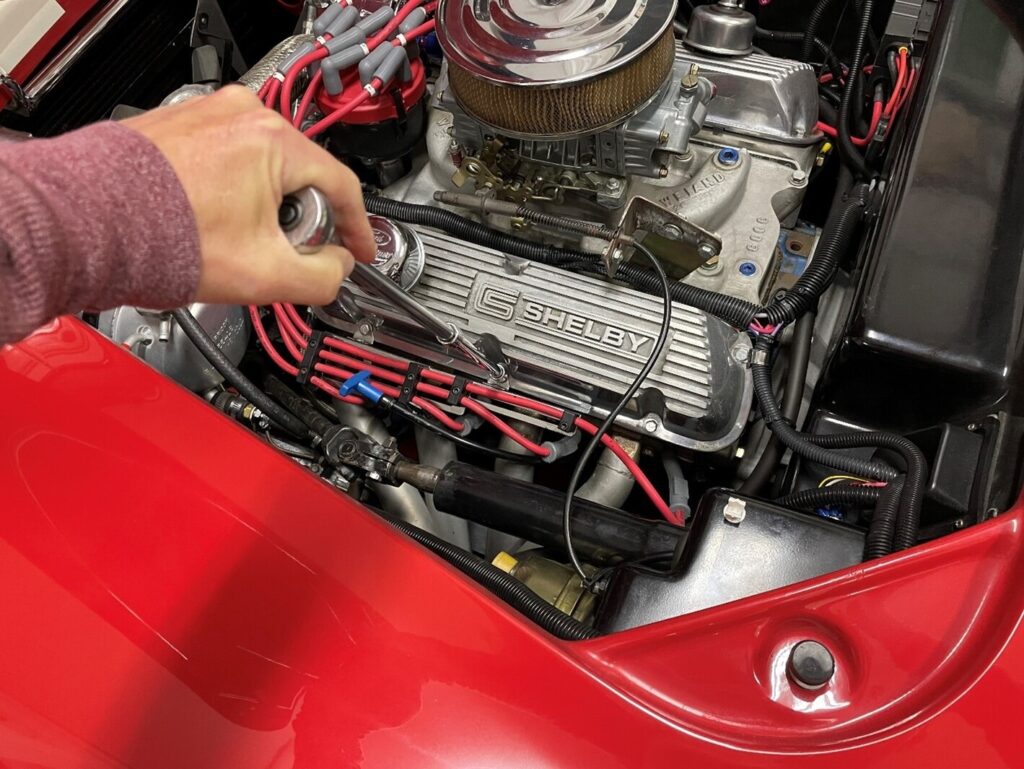 Mechanic working on a Ford engine in a red car for easy classic car projects