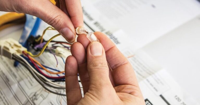 A person installing wire connectors on the radio wiring for a modern sound system