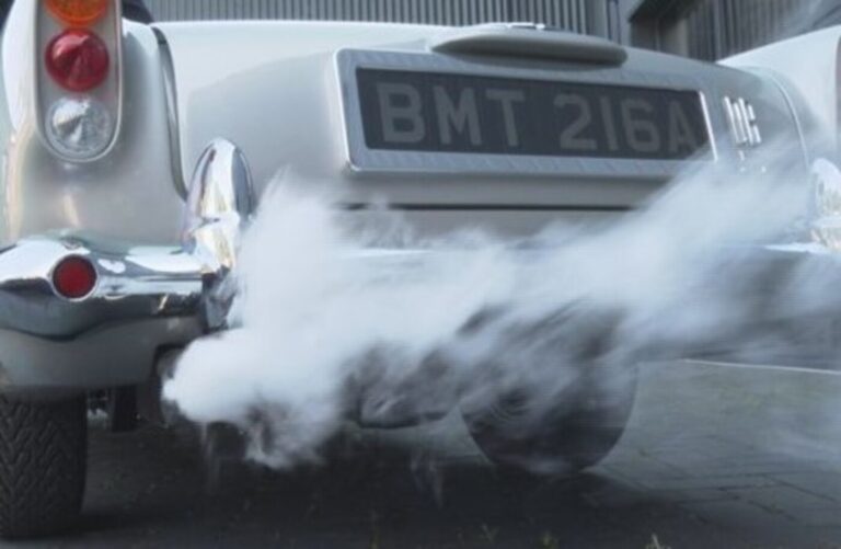 A silver car with gray smokey exhaust