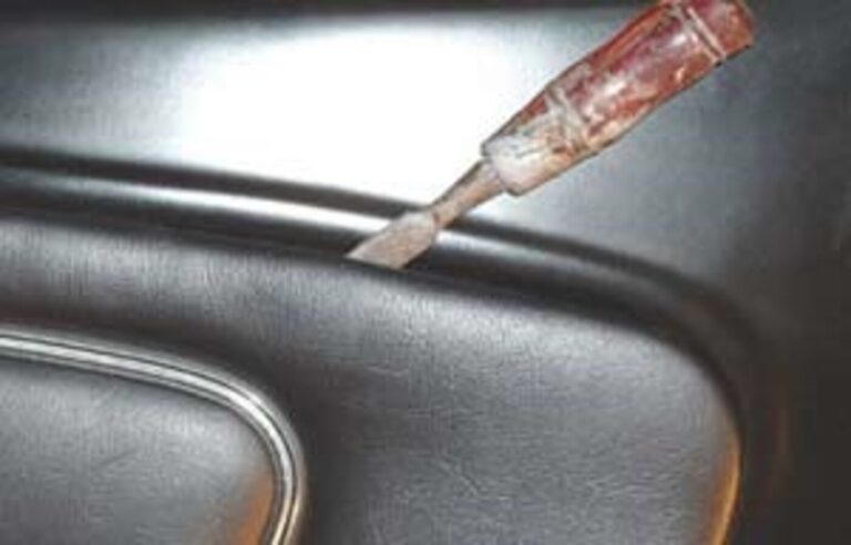 Using a tool to remove the interior car door vinyl panel prior to making repairs to a loose window