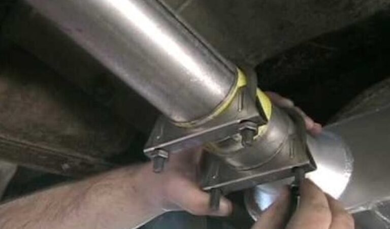 A mechanic working on an exhaust pipe by installing u-bolt exhaust clamps