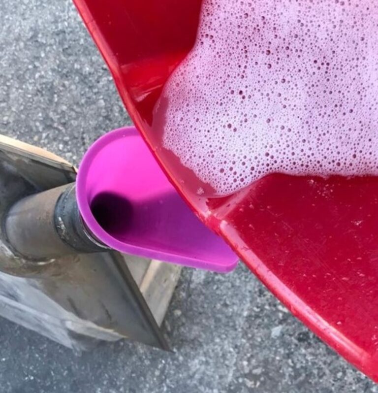 Pouringg fuel tank cleaning solution into a fuel tank from a red bucket thru a pink funnel