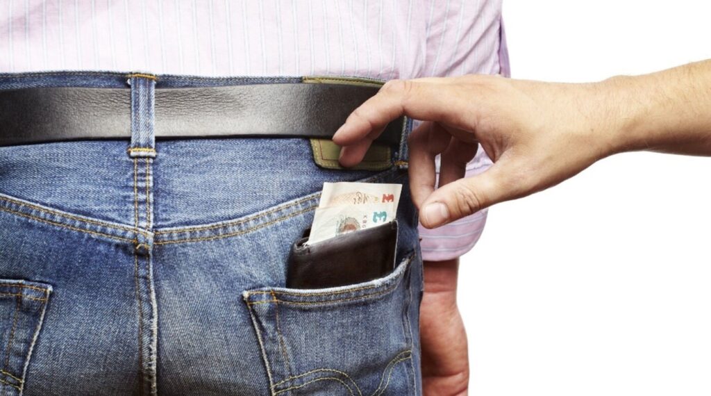 A person reaching into another persons rear jeans pants pocket to take a wallet and money like a restoration scam