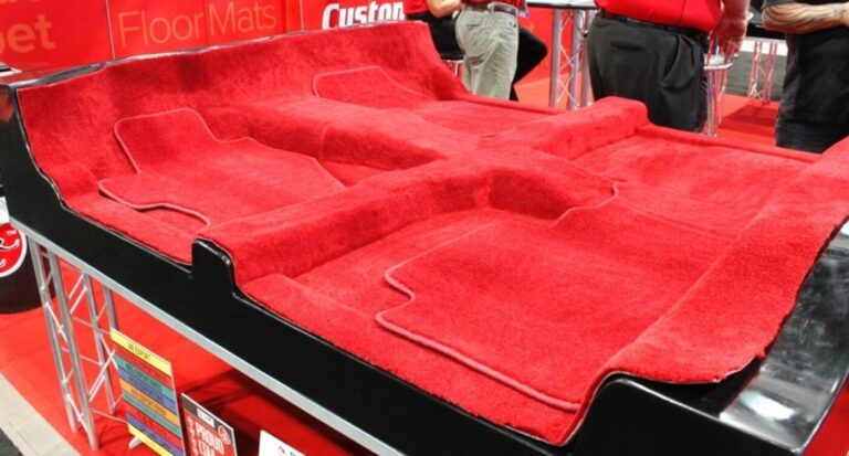 A trade show display with red car's interior carpet and carpeted floor mats