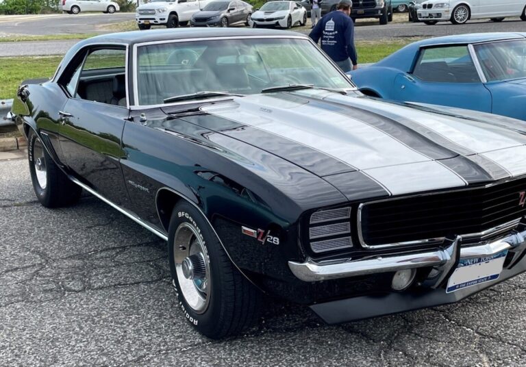 A black 1969 Chevrolet Camaro Z28 parked at a car show next to a blue Corvette, so decide if you want to modify your classic car?