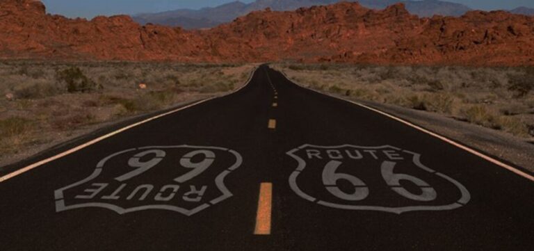 A section of road thru the Arizona desert with Route 66 painted on the pavement for road trips