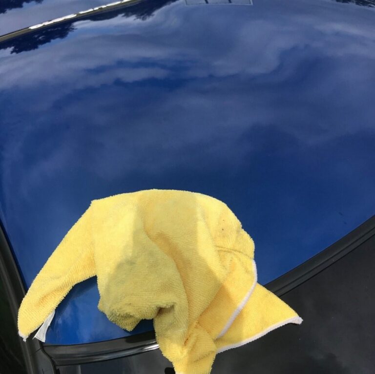 A blue Corvette roof with a yellow microfiber town after car polishing