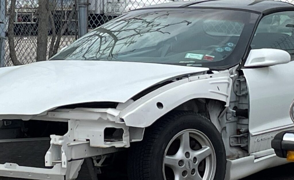 White 3rd generation Chevy Camaro with front end damage waiting on autobody repair