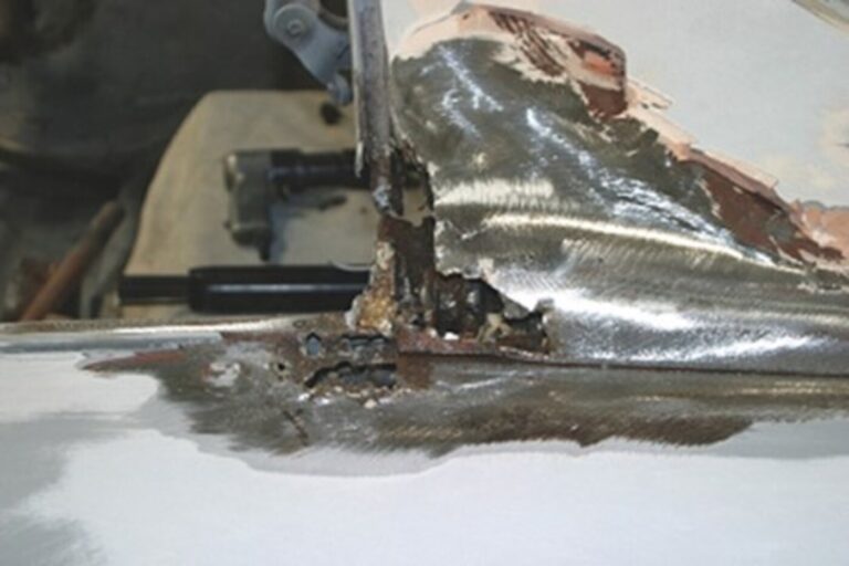 A rusted window panel on a car which will require metal replacement and welding as part of the autobody repair