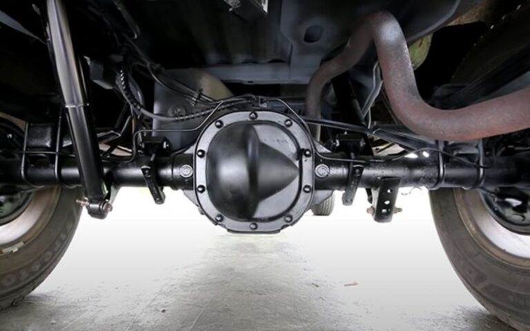 A black truck rear axel and differential with black shock absorbers as part of the truck's suspension components.
